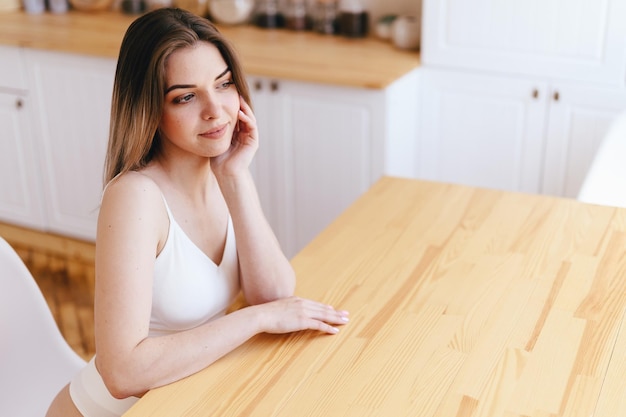 Lovely Young Woman in Smiling sits at Wooden Table Girl Looks out Window Meditate On coming Day