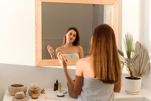 A lovely young woman uses a moisturizing mist spray for glowing skin Moisturizing home care and spa concept