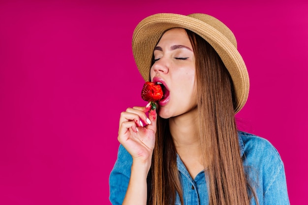 Lover of fruit with pleasure and lust closing her eyes puts strawberry in her mouth