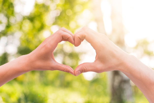 Lovers gesturing heart sign with hands outside