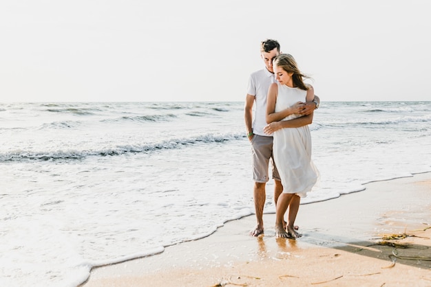 Lovers near the ocean hug and have fun. husband and wife hugs at sunset near the sea. lovers on vacation. summer rest. romantic walk by the ocean