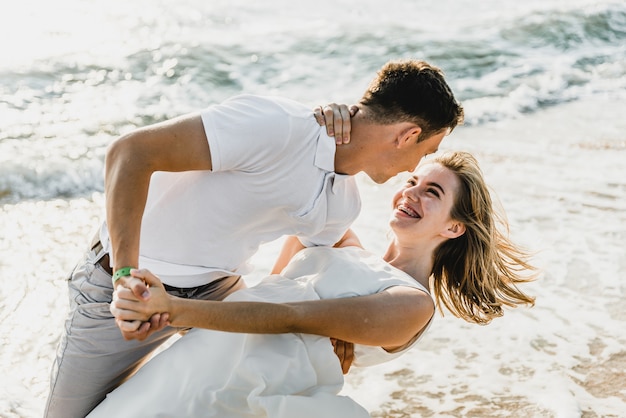 Lovers near the ocean hug and have fun. husband and wife hugs at sunset near the sea. lovers on vacation. summer rest. romantic walk by the ocean