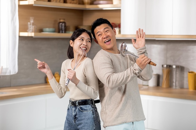 Loving asian spouses singing while cooking together