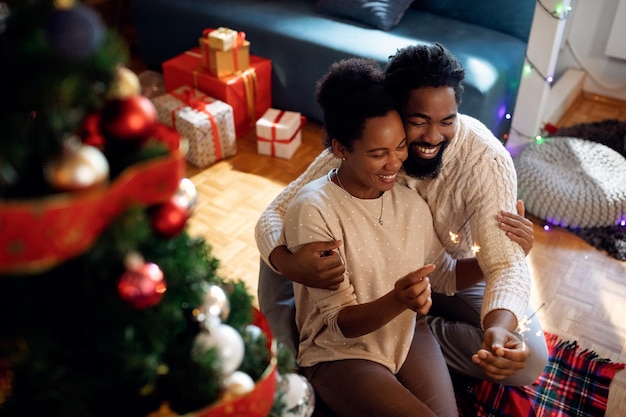 Loving black couple using sparklers while celebrating Christmas at home