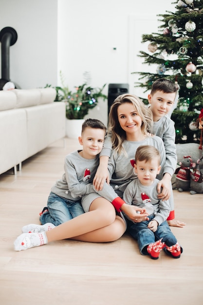 Loving boys hugging their smiling beautiful mother All wearing sweaters with snowman