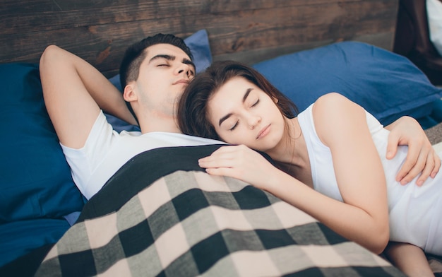 A loving couple are lying on the bed. Bright and cozy bedroom. Family comfort and love.