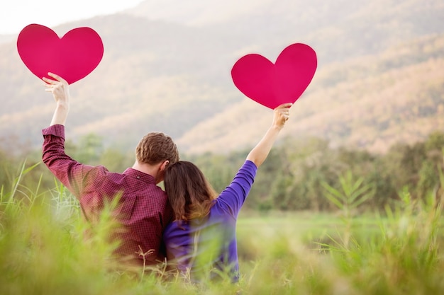 Loving couple. Beautiful young love couple holding paper hearts and smiling in outdoor nature vintage tone, valentine concept