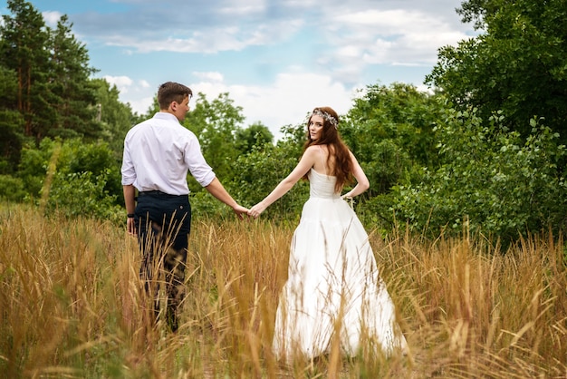 Loving couple bride and groom hold hands in the forest