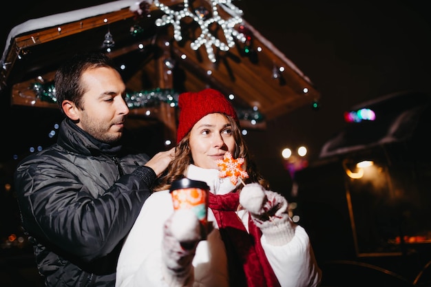 Loving couple in the city walk drink coffee with Christmas candy in winter.