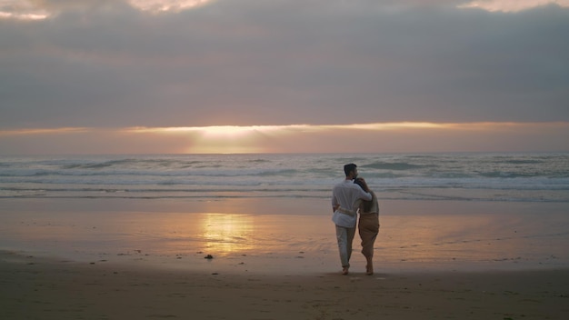 Loving couple crossing sunset seashore summer people embracing at sea nature