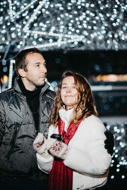 Loving couple in a festive city with New Year's lights in the winter evening. Spouses in winter clot