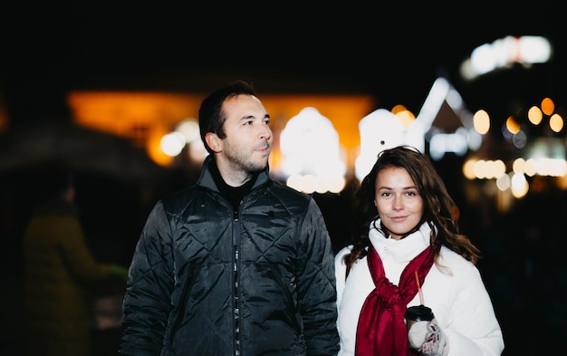 Loving couple in a festive city with New Year's lights in the winter evening. Spouses in winter clot