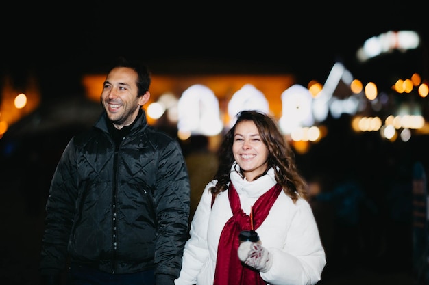 Loving couple in a festive city with New Year's lights in the winter evening. Spouses in winter clot