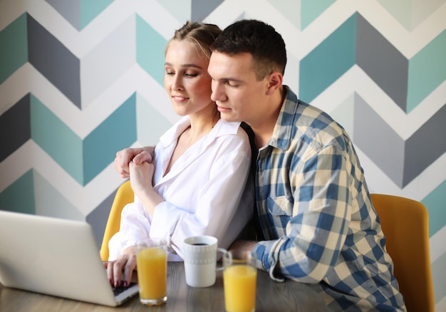 Loving couple having breakfast and looking at laptop computer