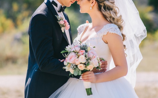 Loving couple holding hands with rings against wedding dress