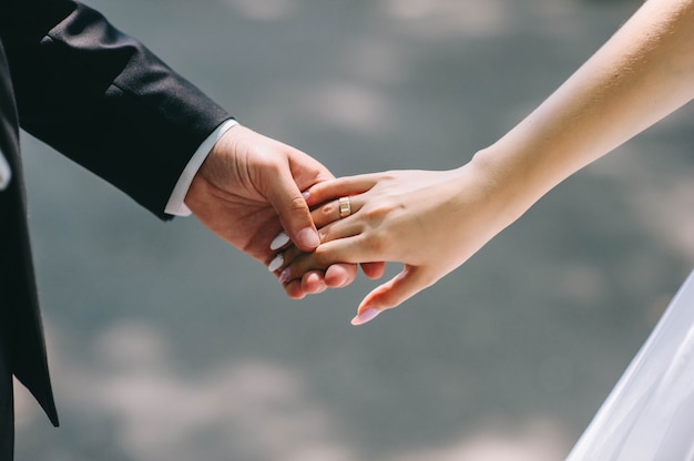 Photo loving couple holding hands with rings against wedding dress