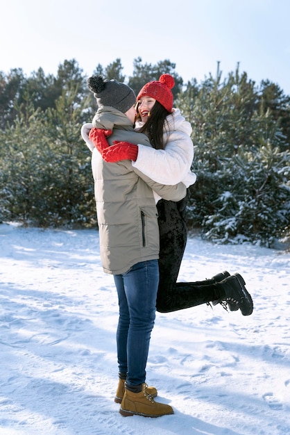 Loving couple hugs on outdoors near snowy forest. Vertical frame.