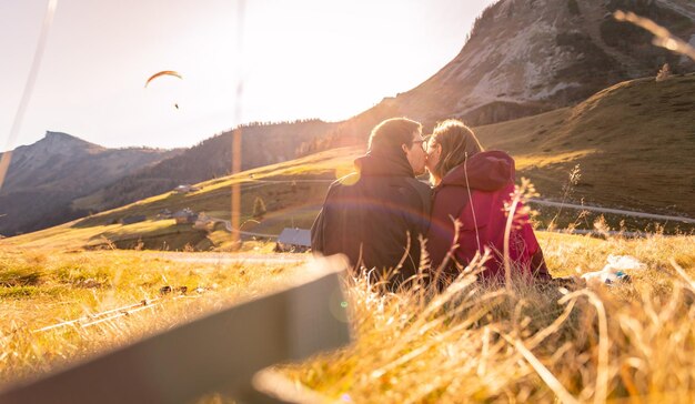 Photo loving couple is enjoying the sundown in the mountains sitting on the ground warm colors alps austria