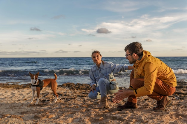 Loving couple is playing with their dog at the beach caucasian people people animal lifestyle and nature concept