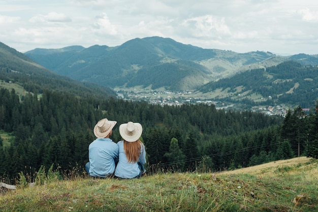 Loving couple sitting on a mountain meadow and enjoying the view of nature