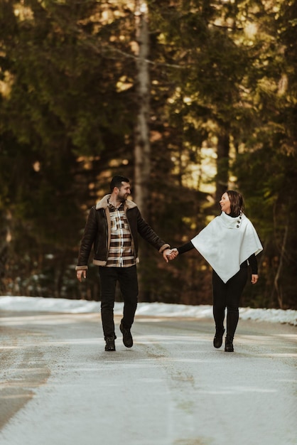 Loving couple walking through snowy frozen highway in winter nature and holding hands. Selective focus. High quality photo