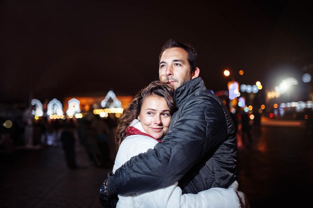 Loving couple walks around the evening Christmas city in winter.