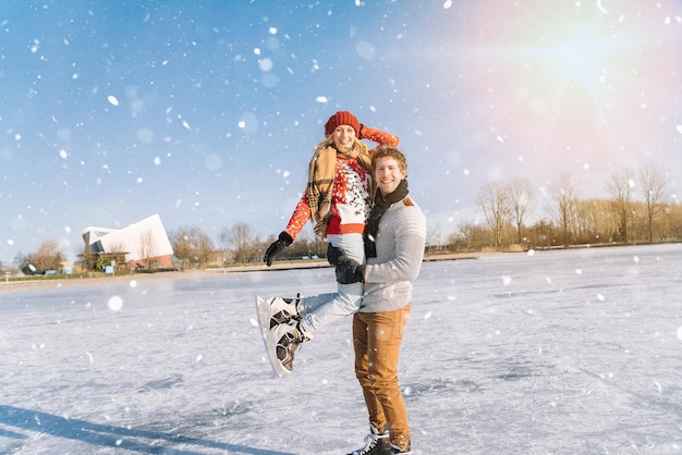 Loving couple in warm sweaters having fun on ice woman and man ice skating outdoors in sunny snowy