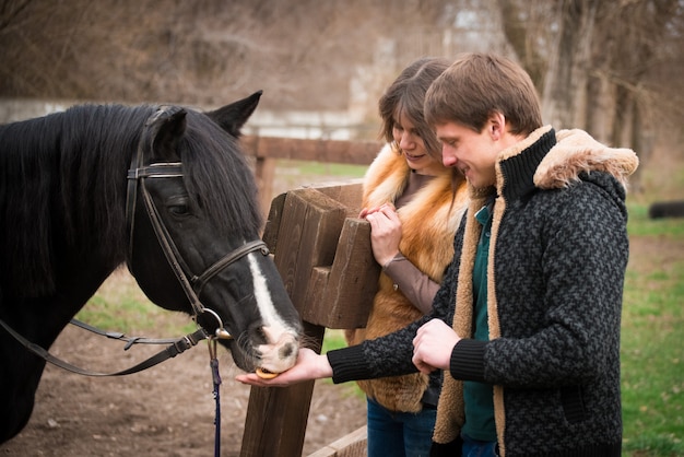 Loving couple with a horse on ranch in an autumn cloudy day.