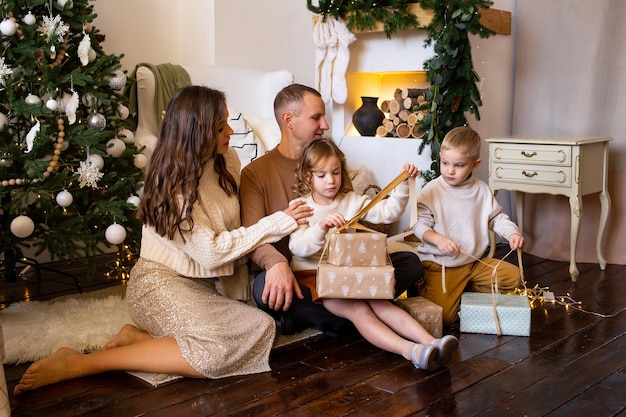 Loving family with presents in room Parent and little children having fun on floor at home near tree indoors