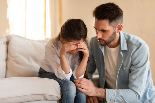 Loving father comforting crying daughter at home