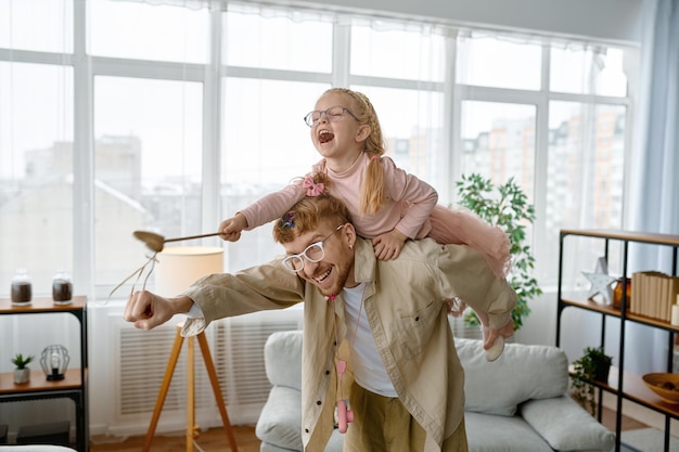 Loving father piggyback riding happy laughing daughter