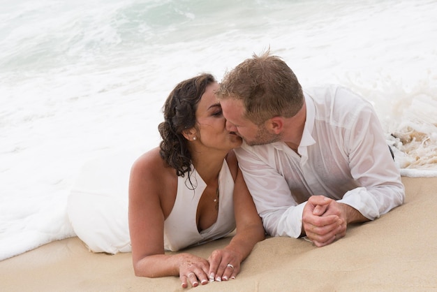 Loving groom kissing bride's mouth on beach