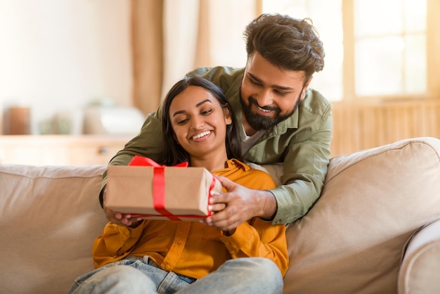 Loving indian husband giving present gift box to wife man celebrating birthday with his beloved