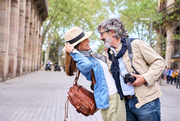 Loving mature couple hugging and looking at in romantic attitude outdoors in city cheerful retired