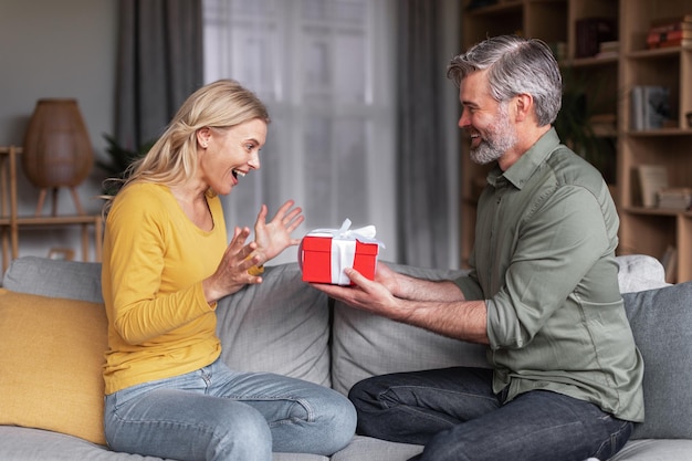 Loving middle aged husband surprising his wife with gift at home