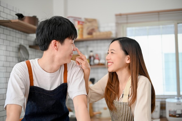 Loving young Asian couple playing while cooking food in the kitchen having romantic moment