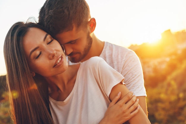 Loving young couple embracing and smiling while spending time outdoors