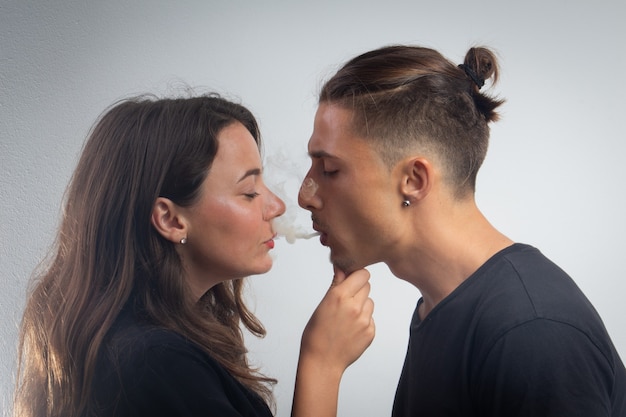 Loving young couple share the smoke of a cigarette