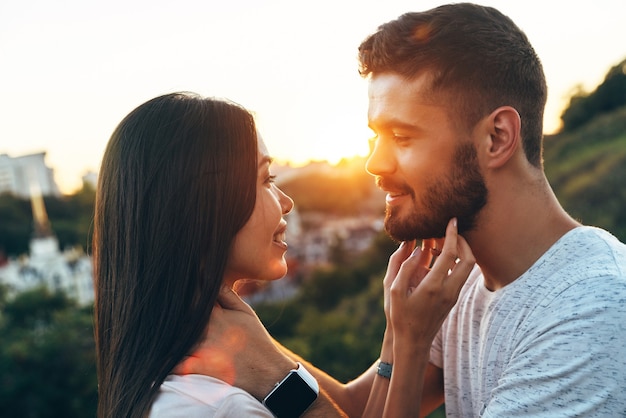 Loving young couple standing face to face and smiling while spending time outdoors