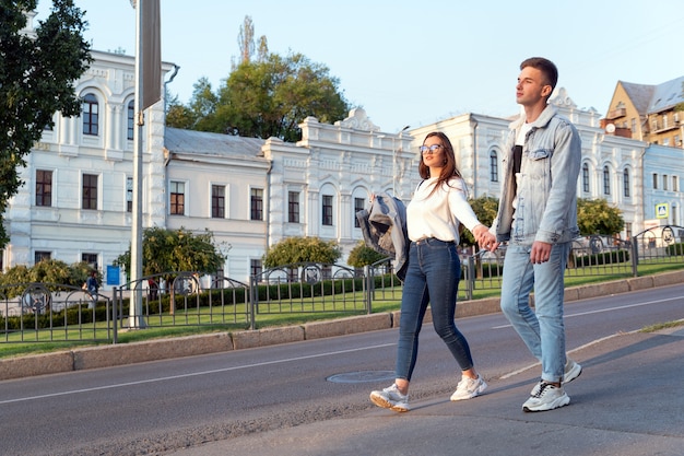 Loving young couple walking around the city holding hands. Blind date.