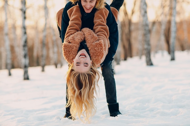 Loving young couple walking playing and having fun in winter forest park