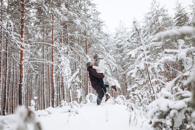 Loving young couple walks in a beautiful snowy forest in winter