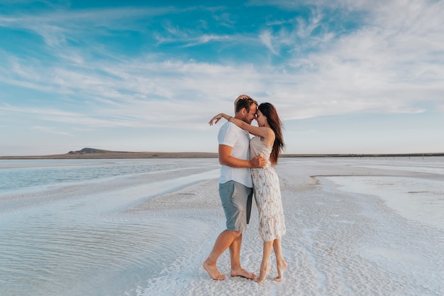 A loving young married couple walks along the seashore. Newlyweds on a honeymoon trip.