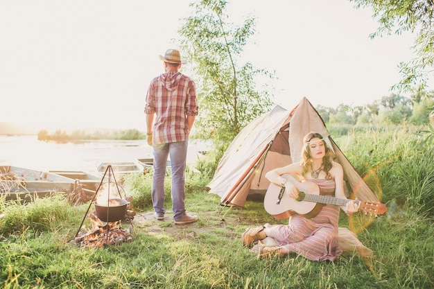 Loving young sexy coupl near camp tent Camping couple in love Couples of lovers tourists relax on nature Camping trip with lovers Carefree coupl near campfire bonfire freedom concept