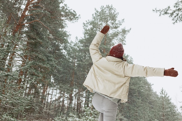 Low angle back view of unrecognizable happy woman jumping with raised arms