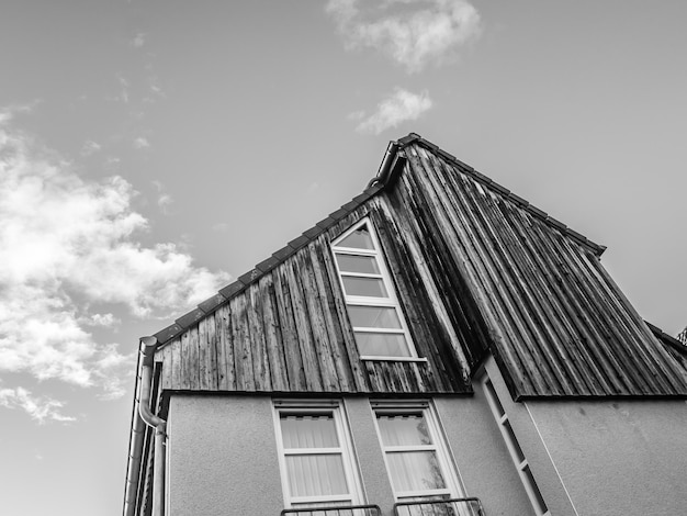 Low angle grayscale shot of a modern wooden house against a cloudy sky