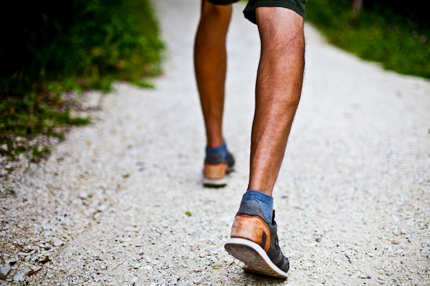 Low angle ground level view with feet of a man on park or forest path.