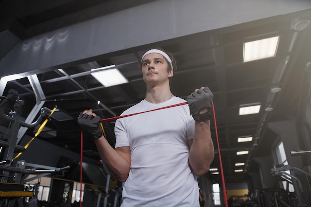 Low angle shot of an athletic man doing biceps curls with resistance band