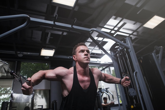 Low angle shot of a bodybuilder working out on crossover cable gym machine