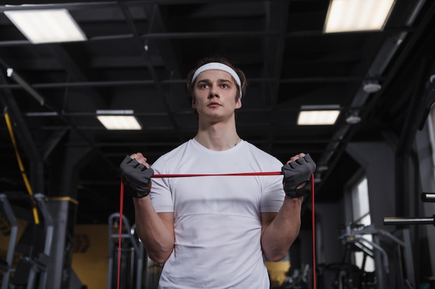 Low angle shot of a sportsman doing biceps workout using resistance band